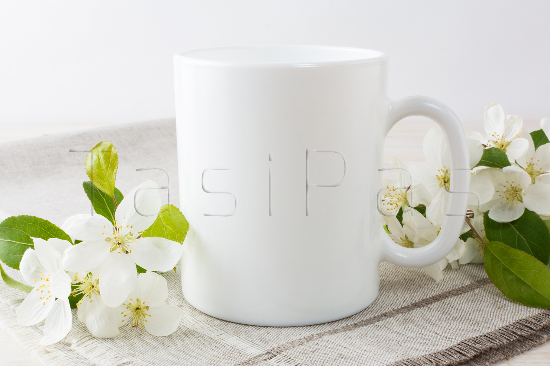White coffee mug mockup with blossoming apple tree branch.