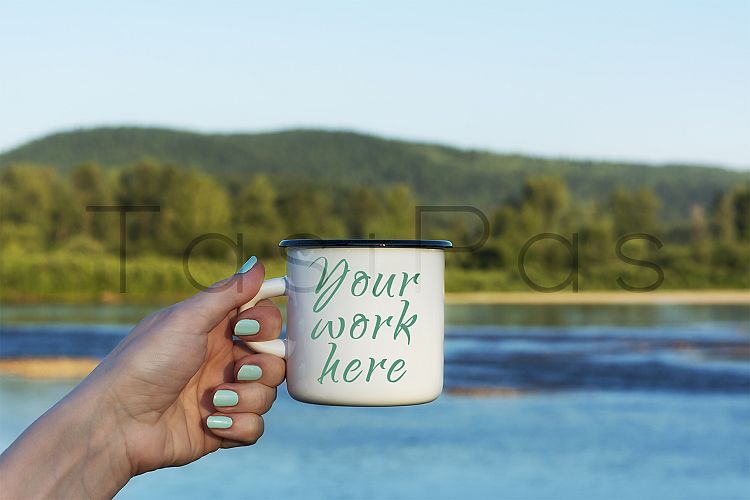 Woman holding enamel mug with river view