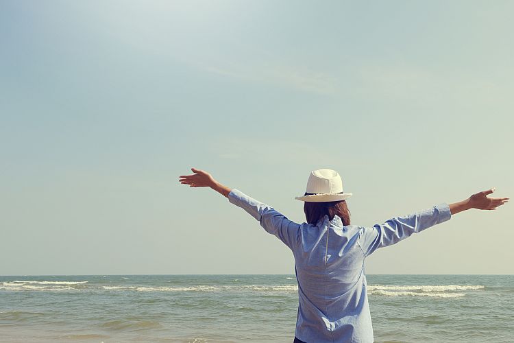young woman standing arms outstretched back and enjoy life