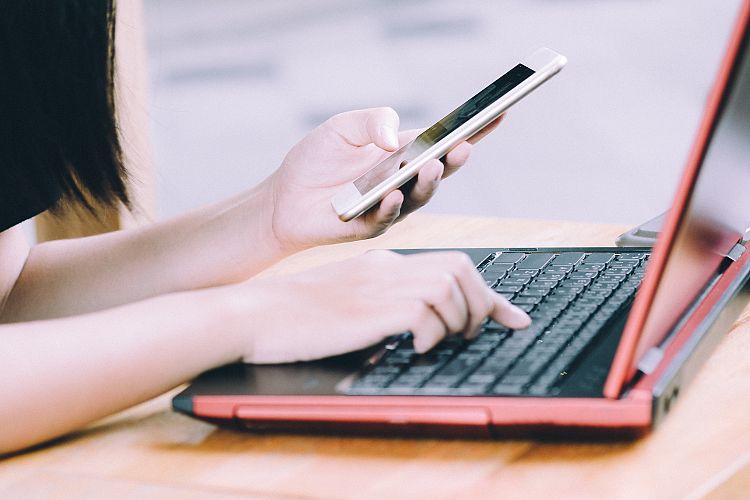 Young hipster woman using smartphone and laptop