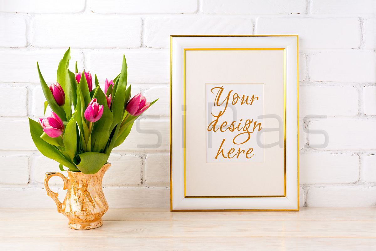 Gold decorated frame mockup with bright pink tulips bouquet in gold jug near white painted brick wall. example image 1