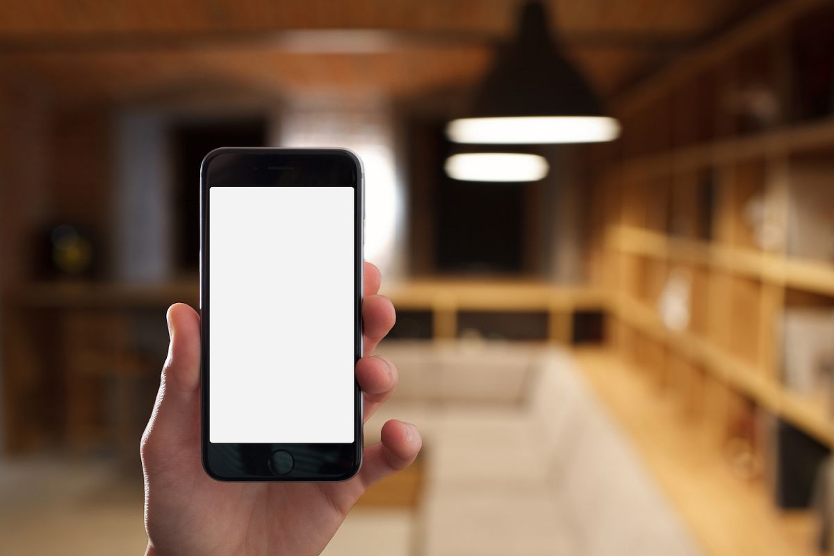 Hand holding mobile smart phone with blank screen in office example image 1