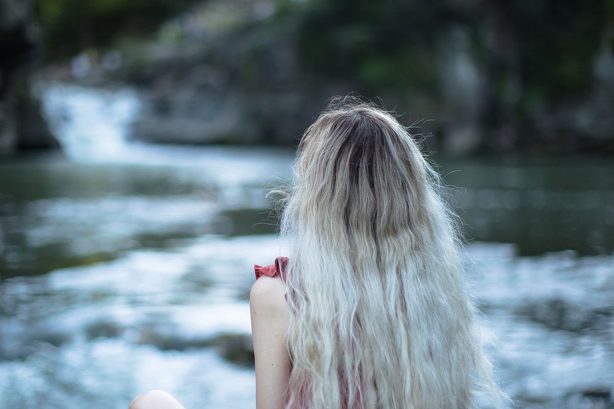 Girl sitting on the rock at the waterfall example image 1