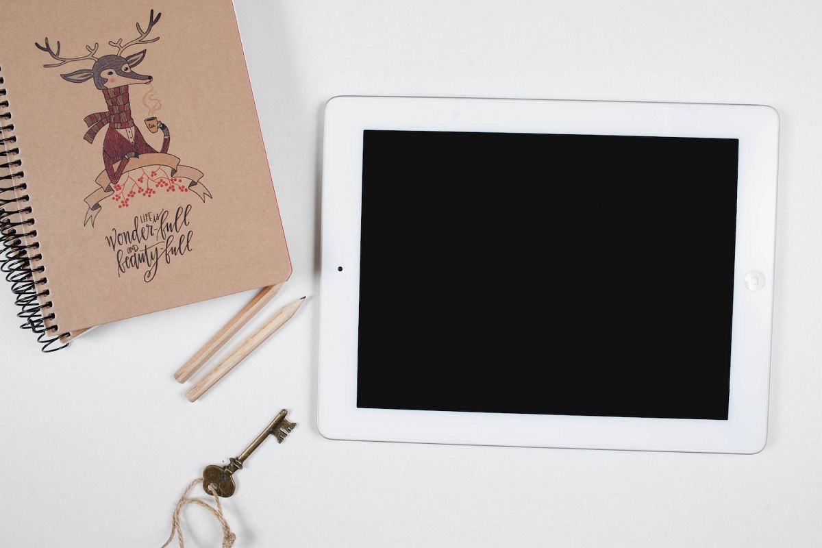 White digital tablet and notebook on white table whit pencils example image 1