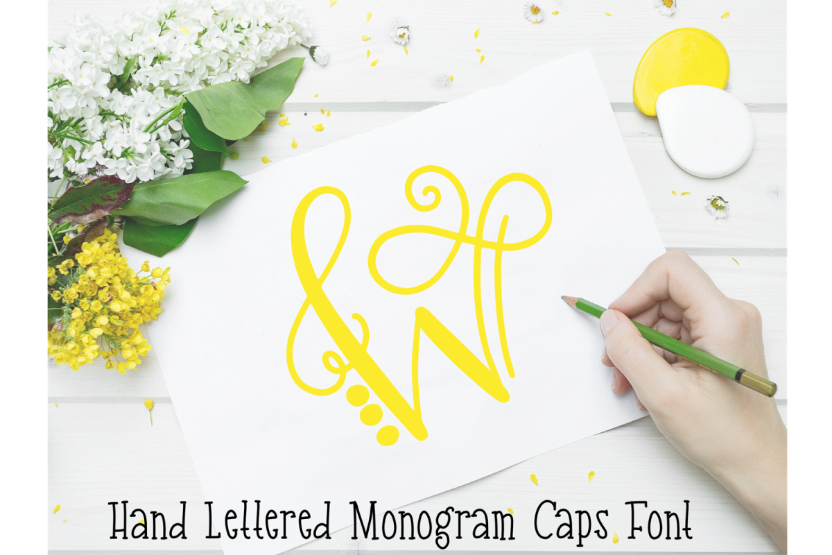 A white table with yellow and white flowers, with a woman's hand drawing a yellow "W" on white paper. It is a hand lettered monogram font. Download thousands of free fonts to use with your Cricut machine. 