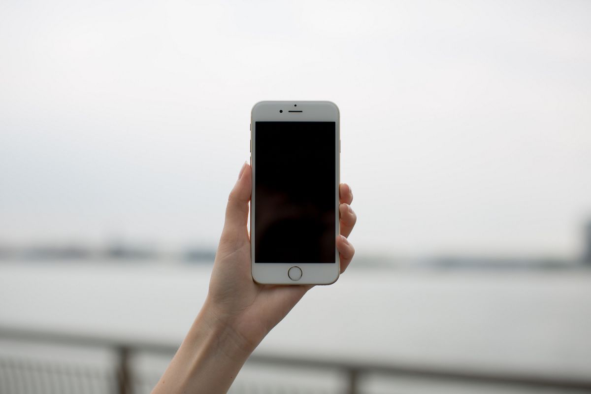 Female hand holding smartphone ,blur river whit bridge on background example image 1