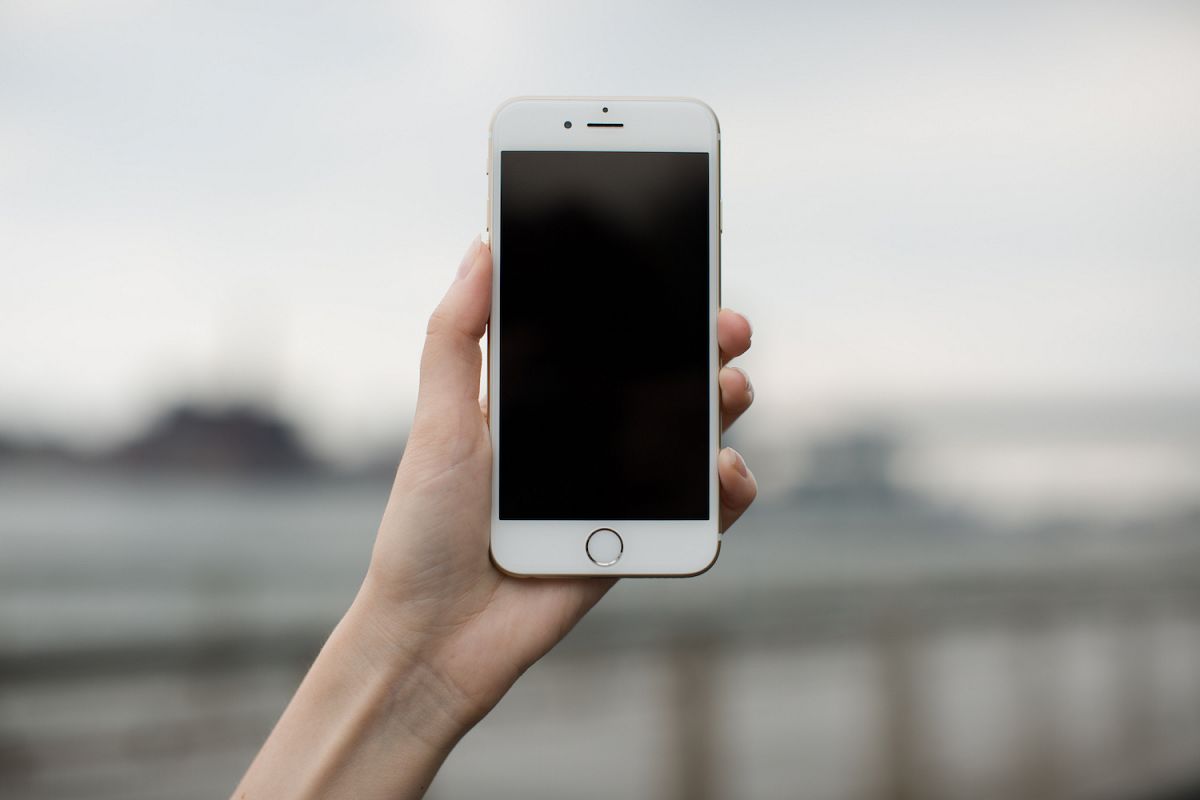 Female hand holding iPhone 8 ,blur river whit bridge on background example image 1